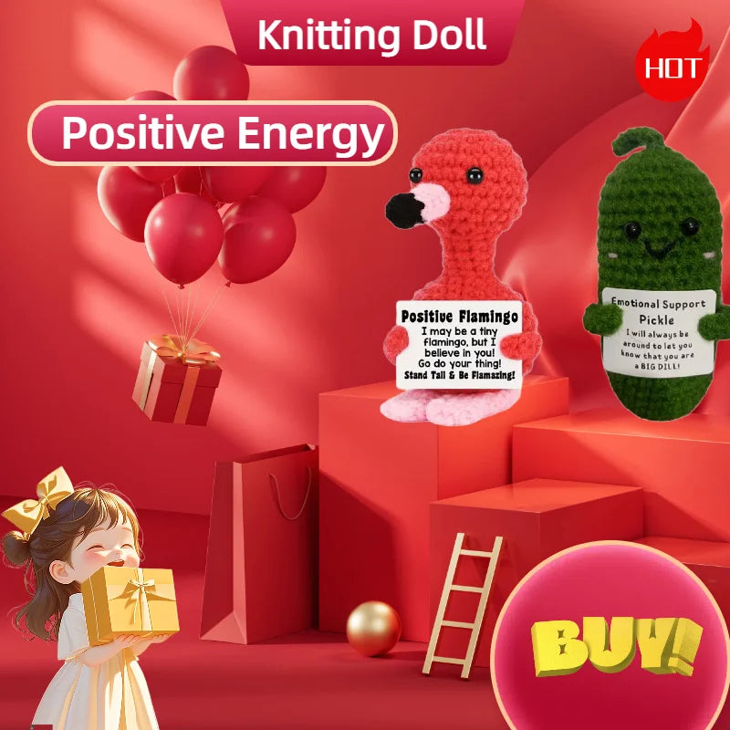 A knitted doll with a pink nose and green body is displayed in a red room setting with balloons and gifts.
