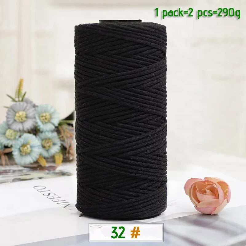 A black spool of medium-thick hand-woven cotton yarn for crafting, with a single ball visible nearby.