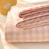 Pink organic cotton bedding set with folded flat sheets and a yellow heart-shaped object.