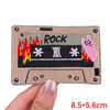 A rectangular embroidery patch featuring the word ROCK and a rose skull design on a beige fabric background.