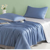 A blue ice silk cooling quilt is displayed on a bed with white linens and a light green wall.