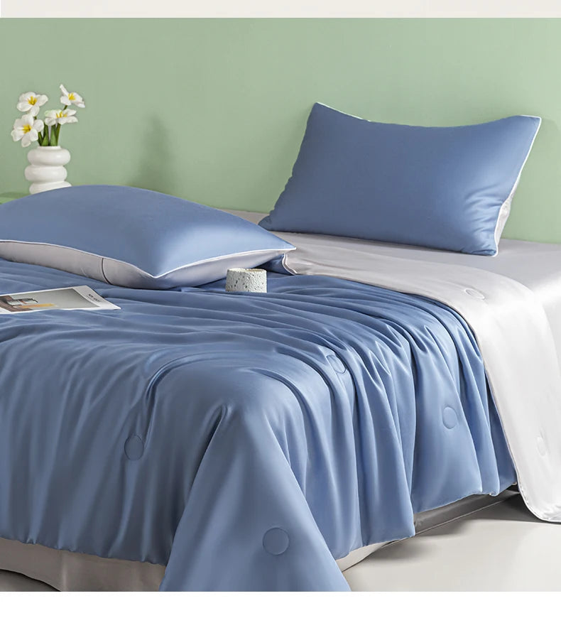 A blue ice silk cooling quilt is displayed on a bed with white linens and a light green wall.