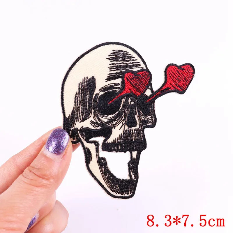 A hand holds a black and white rose skull embroidery patch for clothing.