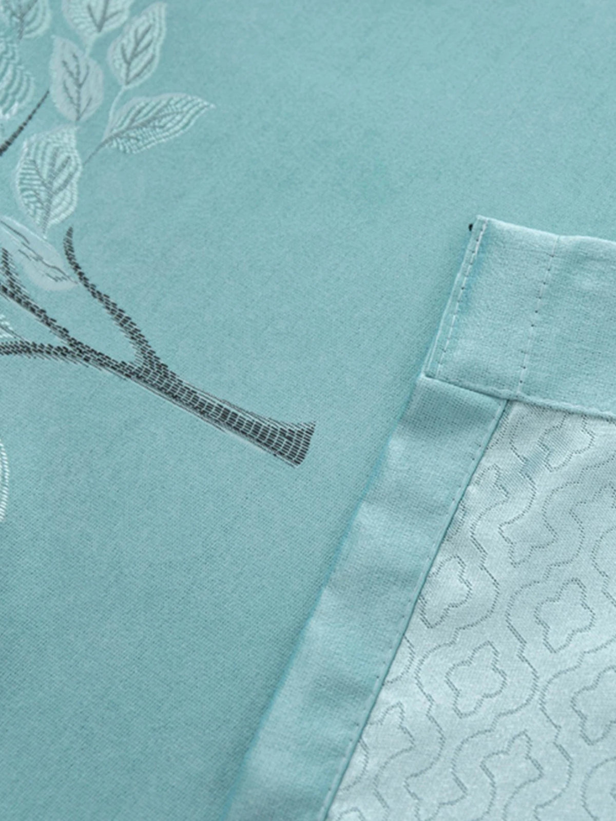 Light blue fabric featuring a delicate black line drawing of branches and leaves.
