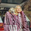 A woman smiling while holding an ultra-soft flannel throw blanket for mom in the back of a car.