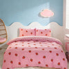 Pink strawberry print duvet cover set displayed on a white bed with a light blue wall and a cloud light.