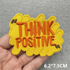 Yellow embroidered patch with orange text that reads THINK POSITIVE