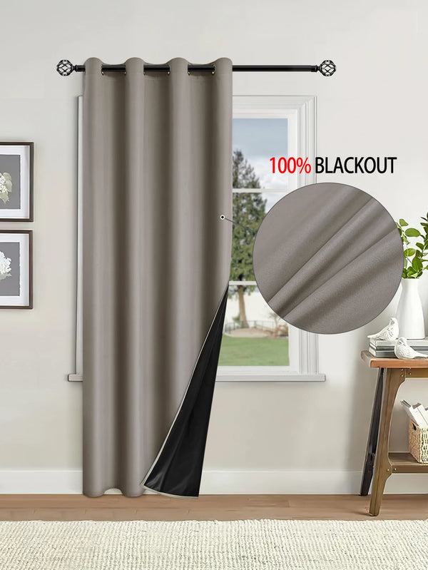 A floor-length gray blackout curtain hanging on a rod next to a window.