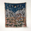 A dark blue throw blanket featuring a celestial scene with crescent moons and a field of colorful wildflowers.