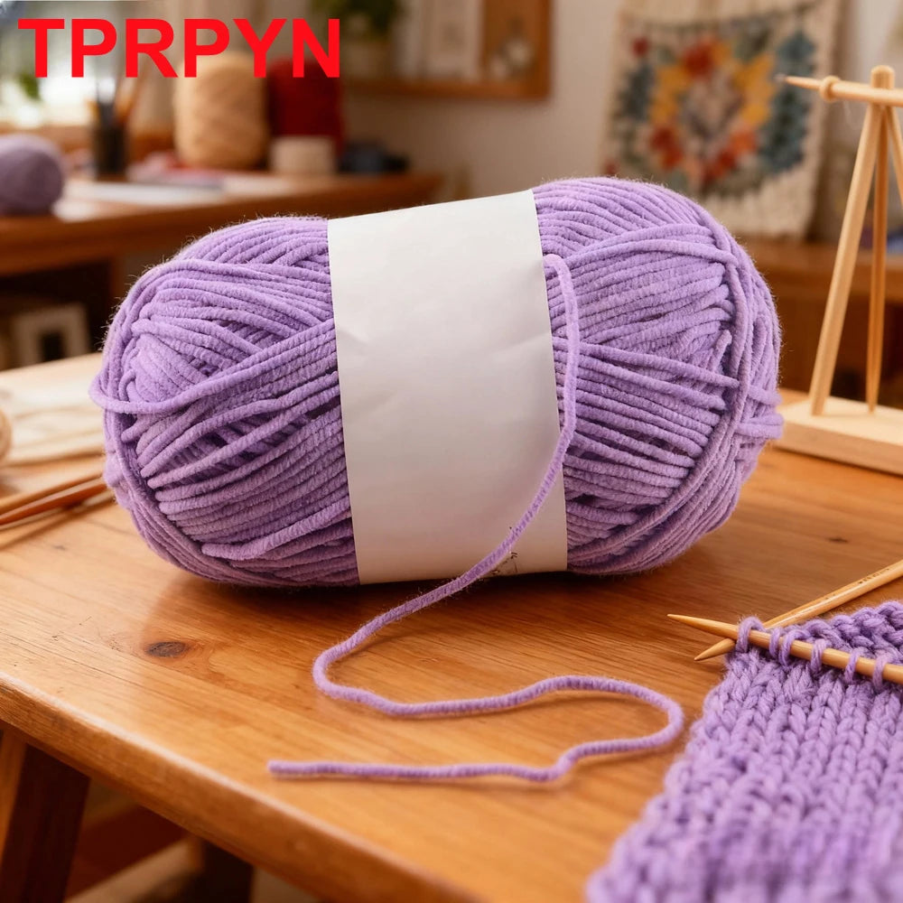 Purple soft bulky chenille yarn skein with a white label and loose strands on a wooden table.