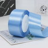 Roll of light blue satin ribbon with white filling shown next to a piece of paper