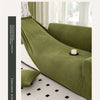 A deep olive green stretch jacquard sofa slipcover in a modern living room setting.