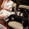 A black animal plush sofa cushion is shown next to a person sitting in a light-colored chair.