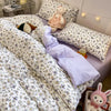 A close-up of a pink floral bedding set featuring a duvet and pillows with white and yellow patterns.