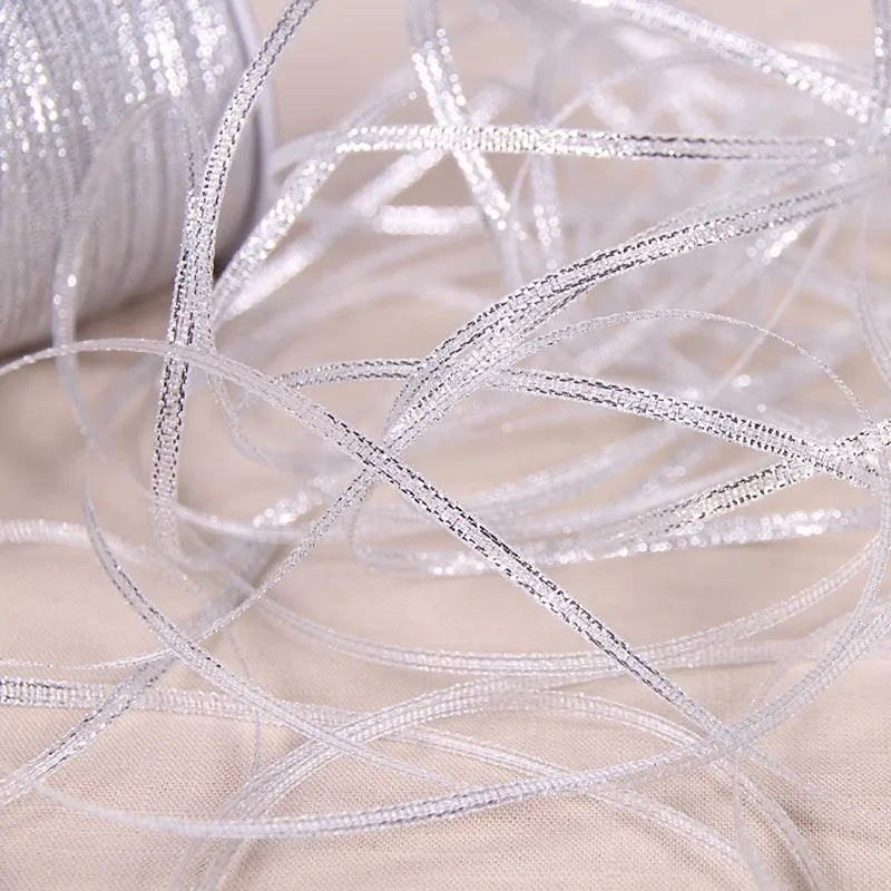 A close-up of gold and silver glitter satin ribbon strands lying on a light fabric.