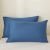 A set of three solid blue linen pillows resting on a white surface.