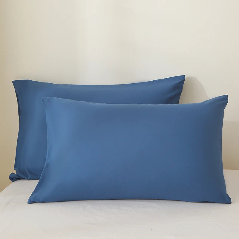 A set of three solid blue linen pillows resting on a white surface.