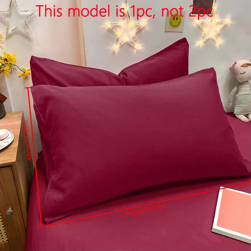 A close-up of a maroon pillowcase on a bed with decorative star lights in the background.