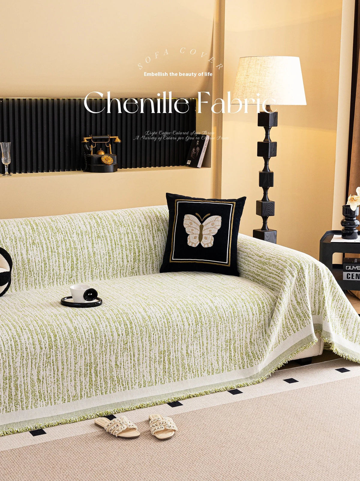 A light green jacquard sofa cover blanket draped over a sofa, with decorative pillows and a lamp in the background.