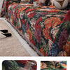 A richly colored floral jacquard sofa throw blanket draped over a sofa with decorative pillows.