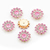 A collection of pink and clear rhinestone crystals in flower shapes, including round and starburst designs.