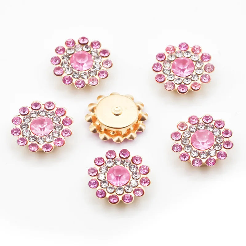 A collection of pink and clear rhinestone crystals in flower shapes, including round and starburst designs.