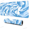 A blue and white swirling vortex design on a large extended mouse pad with a non-slip rubber base.