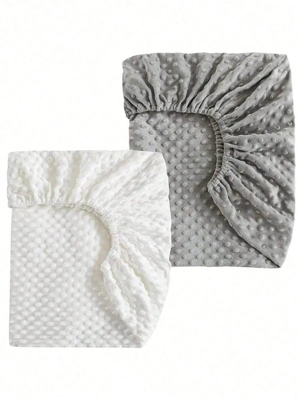 A pair of soft plush mattress and diaper changing covers in white and gray.