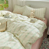 A light green and white floral microfiber duvet set displayed on a bed with a cream-colored pillow and a small rabbit plush t