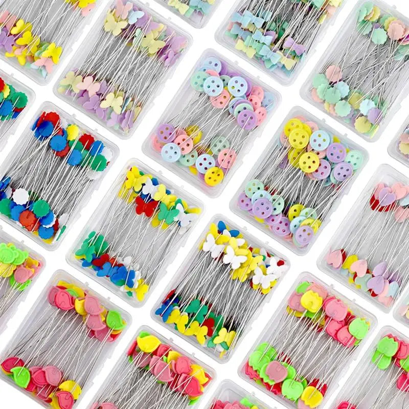 Assortment of nickel-plated dressmaking pins with colorful heads in clear plastic boxes.