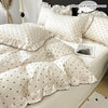 A set of white Korean lace duvet covers and pillow covers with black polka dots displayed on a bed.