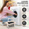 A woman is shown using a white laundry basket to place microfiber pillowcases into a white washing machine.