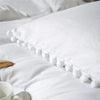 White duvet cover featuring a decorative border of white pom-poms on a bed.