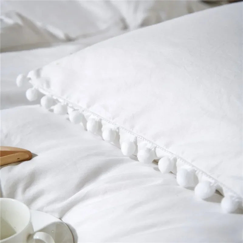 White duvet cover featuring a decorative border of white pom-poms on a bed.