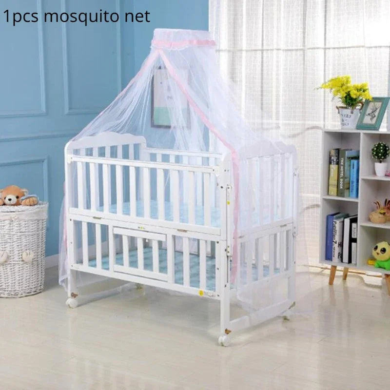 White crib with a sheer mosquito net covering, displayed in a brightly lit room.