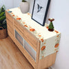 A wooden cabinet with an autumn harvest table runner featuring orange and green floral designs.
