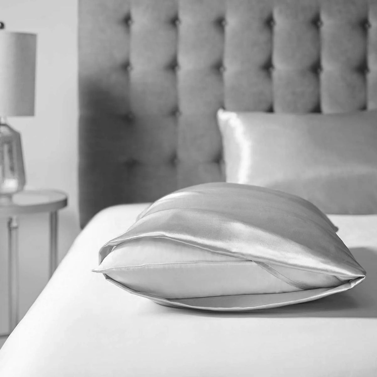 A close-up of a silky satin pillowcase resting on white bedding.
