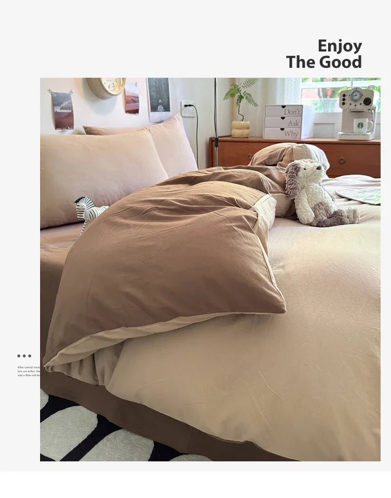 A beige quilt bedding set with a brown duvet and pillows on a bed, next to a lamp and a camera.