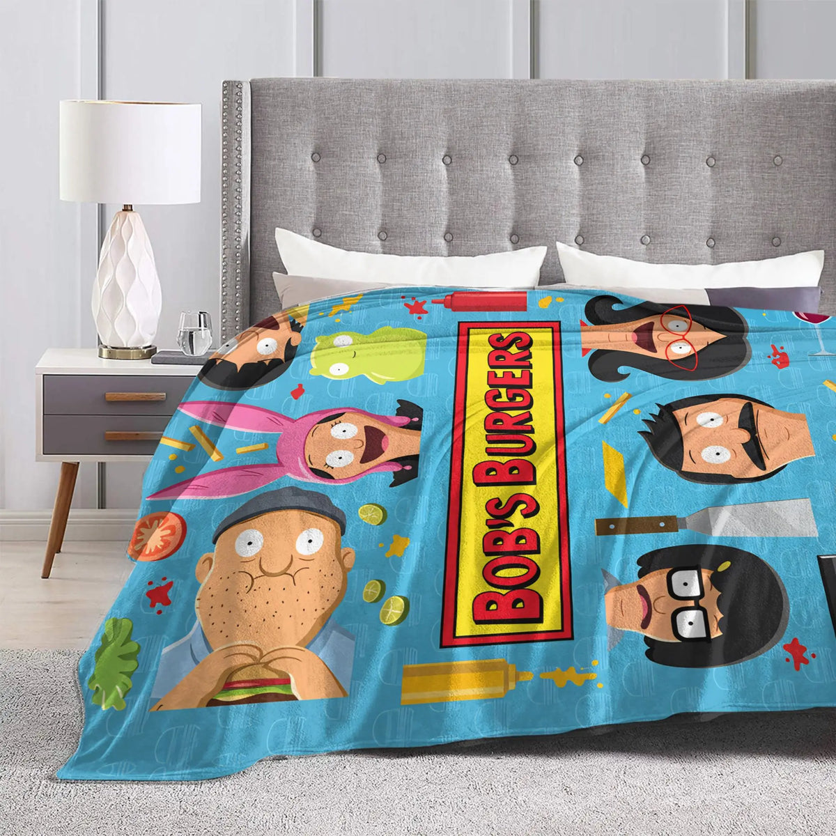 A blue throw blanket featuring cartoon characters and text on a bed.
