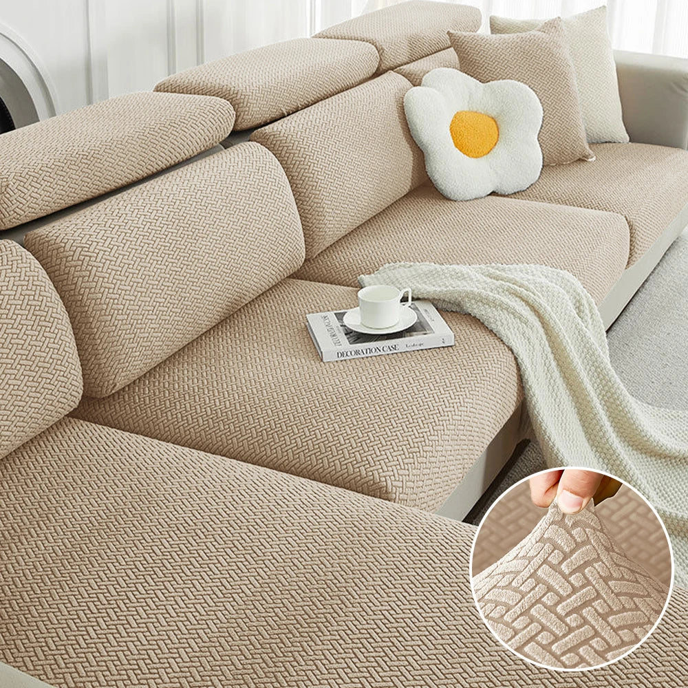 A beige jacquard elastic sofa cushion slipcover with decorative pillows and a cream-colored throw blanket.