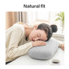A woman rests her head on a gray memory foam neck and travel pillow indoors.