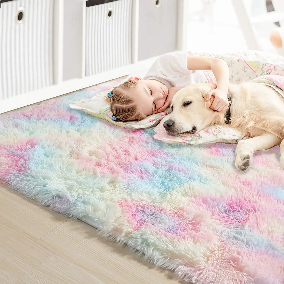 A golden dog is resting on a colorful plush area rug with a child sleeping nearby.