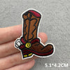 An embroidered patch of a brown cowboy boot with red and yellow detailing on a hand.