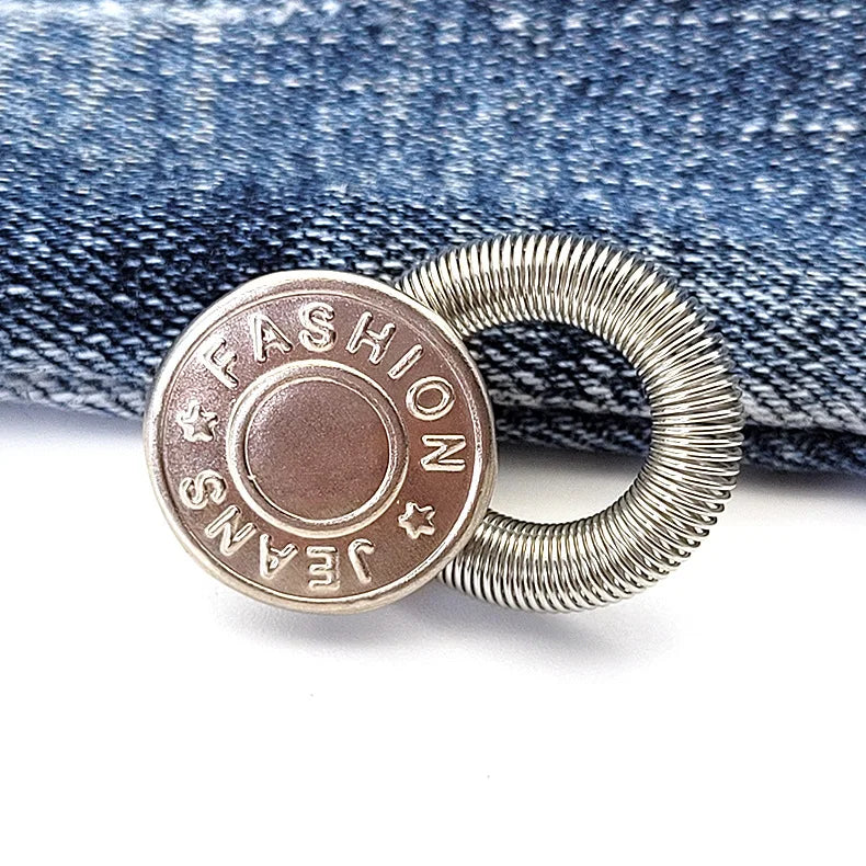 Silver oval button with the text FASHION JEANS embossed on it, resting on a denim fabric.