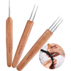A set of wooden crochet hooks for dreadlocks and braids shown next to a hand demonstrating their use.