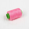 A pink spool of handmade sewing thread with a green tip.