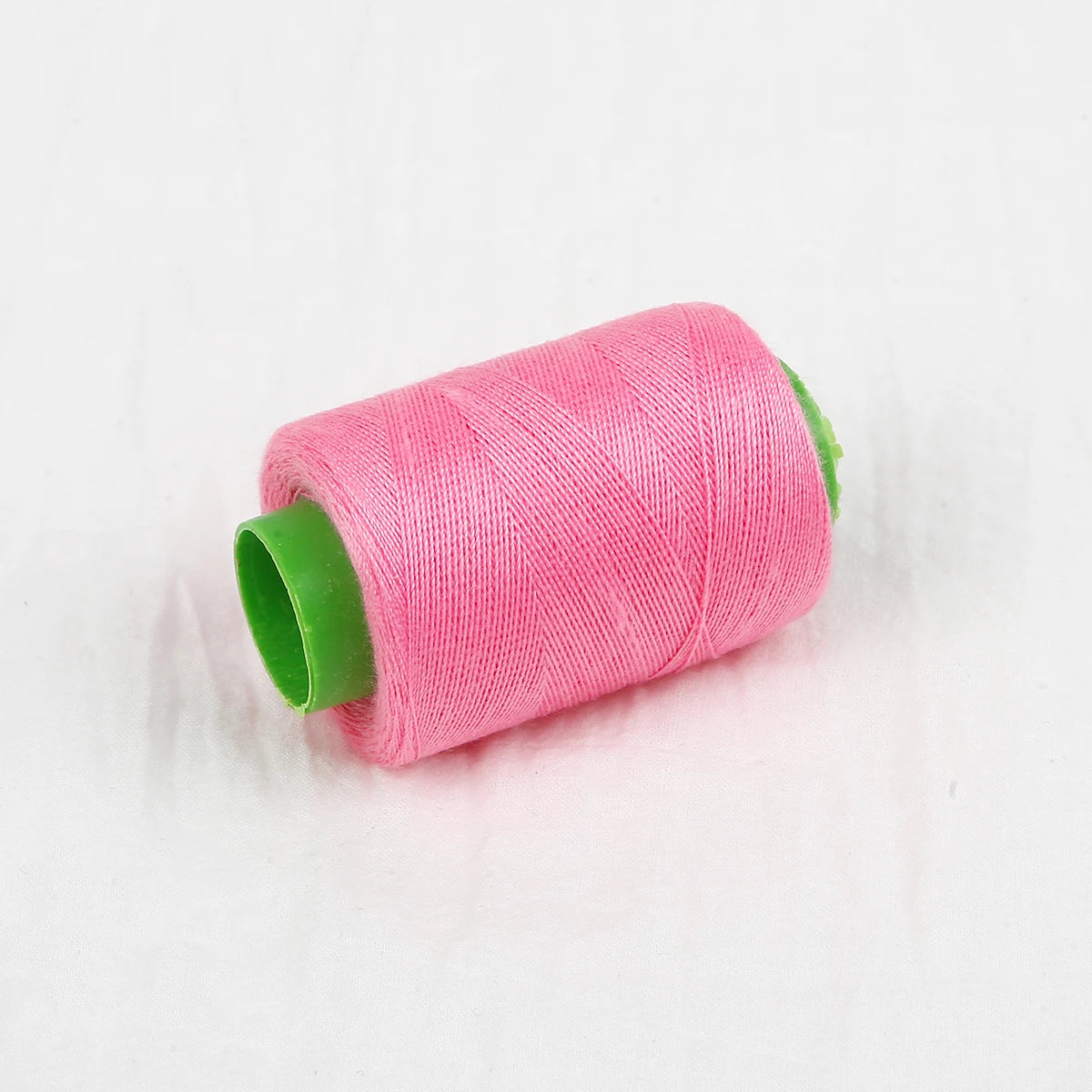 A pink spool of handmade sewing thread with a green tip.