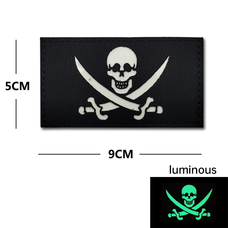 Black embroidery patch featuring a white skull and crossed swords design on tactical gear.