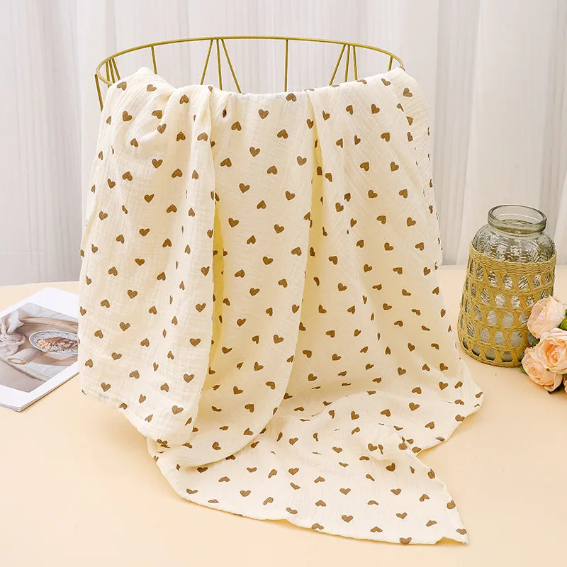 Cream printable cotton crib sheets with small gold hearts hanging on a brass hanger.