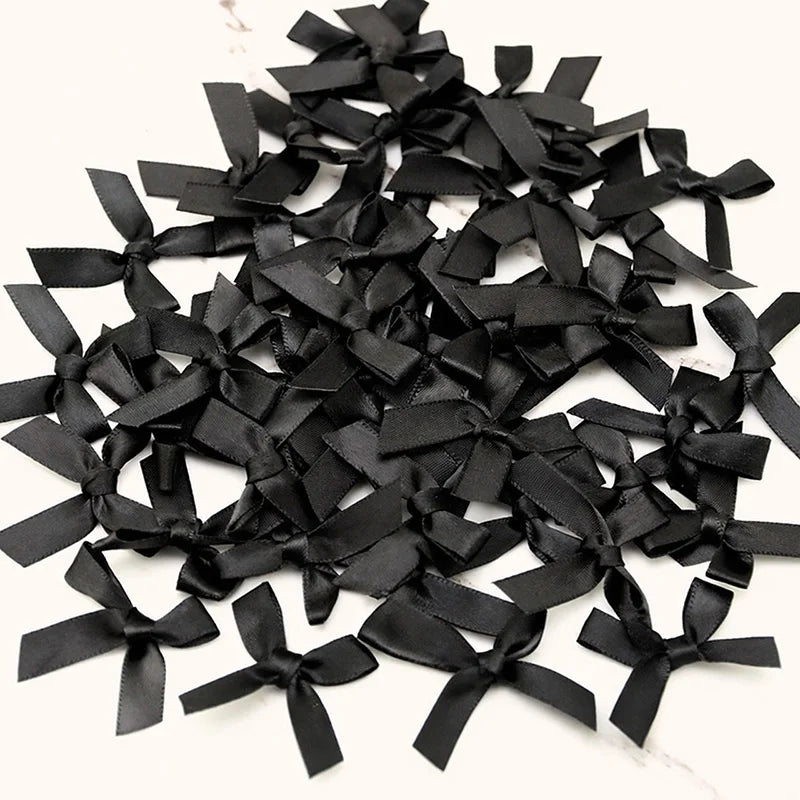 A pile of small black satin ribbon bows for crafts and decor.
